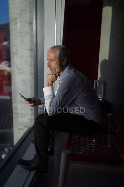 Задумчивый бизнесмен смотрит в окно гостиничного номера — стоковое фото