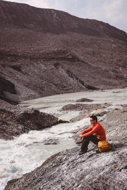 Escursionista maschio con zaino relax vicino al fiume — Foto stock
