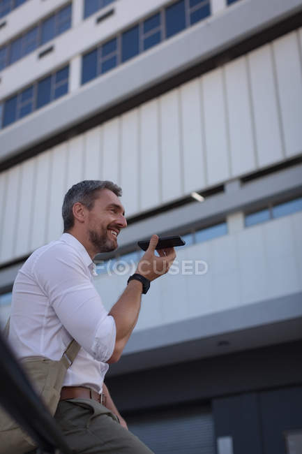 Усміхнений чоловік говорить на мобільному телефоні біля офісної будівлі — стокове фото