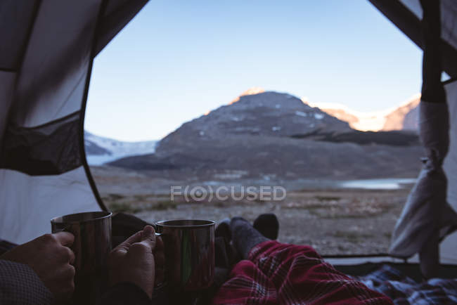 Section basse du couple prenant un café dans la tente — Photo de stock