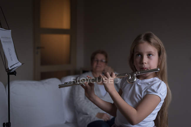 Menina tocando flauta na sala de estar em casa — Fotografia de Stock