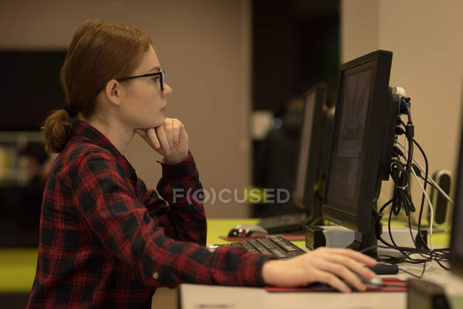Mujer joven usando una PC de escritorio en la biblioteca - foto de stock