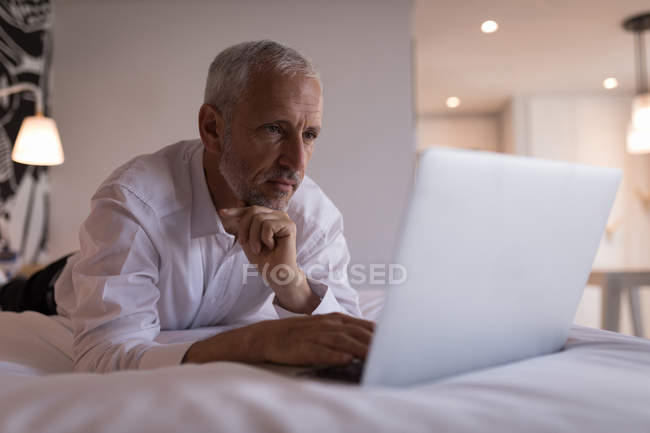 Businessman using a laptop on bed in the hotel room — Stock Photo