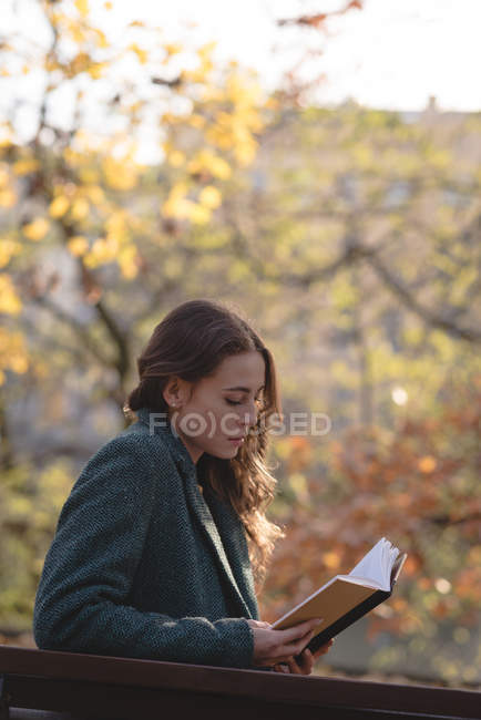 Giovane donna che legge un libro nel parco — Foto stock