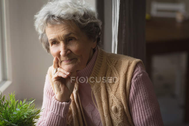 Mujer mayor reflexiva sonriendo en casa - foto de stock
