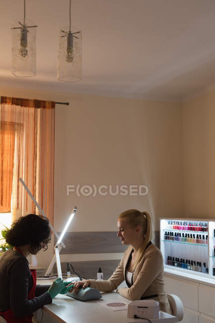 Косметик проводит маникюр для женщин-клиентов в гостиной — стоковое фото
