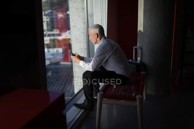 Thoughtful businessman using mobile phone in hotel room — Stock Photo