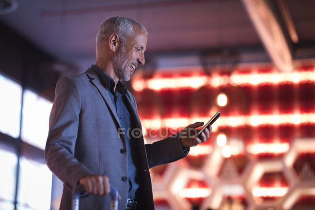Zufriedener Geschäftsmann mit Smartphone beim Betreten des Hotels — Stockfoto