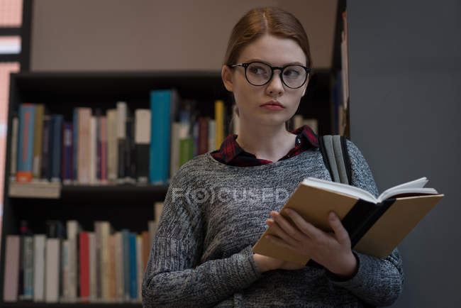 Junge Frau liest ein Buch in der Bibliothek — Stockfoto