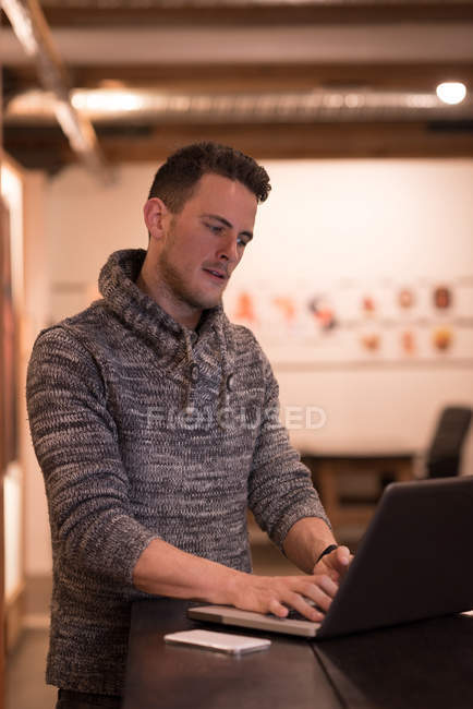 Jovem executivo masculino usando laptop no escritório — Fotografia de Stock