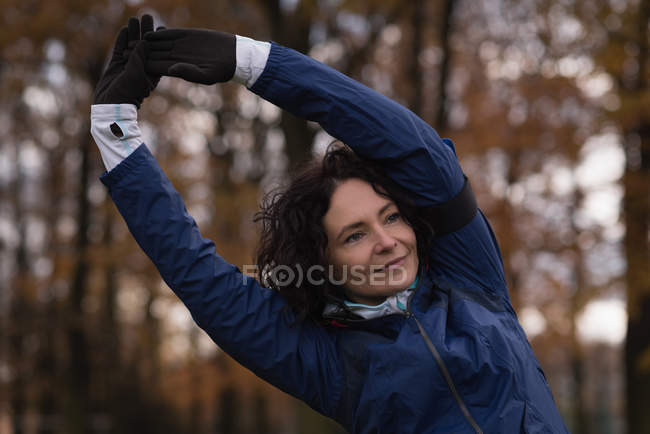 Mujer joven realizando ejercicio de estiramiento en el parque - foto de stock