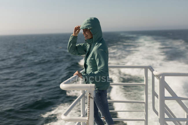 Femme en sweat à capuche debout sur un bateau de croisière par une journée ensoleillée — Photo de stock