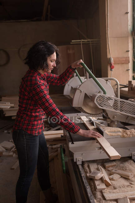 Scie à coupe femme avec scie électrique dans un atelier de menuiserie — Photo de stock