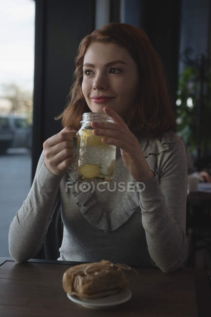 Улыбающаяся женщина пьет лимонный чай в кафе — стоковое фото