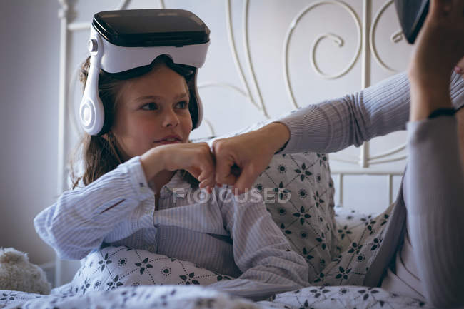 Mother and daughter giving feast pump to each other on bed — Stock Photo