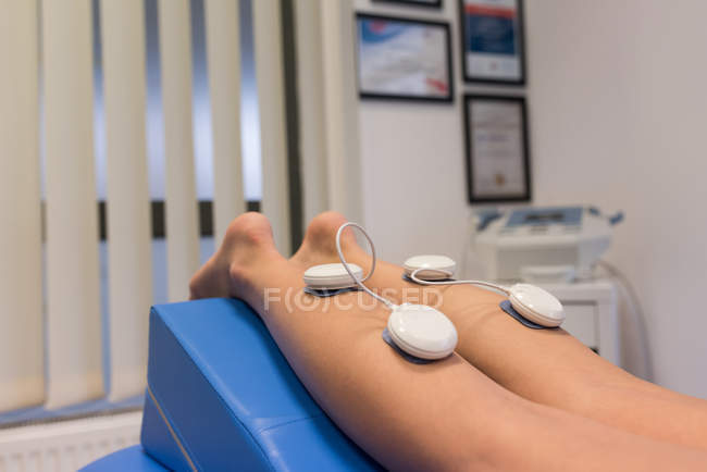 Donna sdraiata con elettrodi sulla gamba in clinica — Foto stock