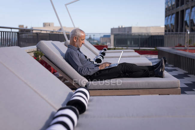 Бізнесмен з ноутбуком відпочиваючи на шезлонгу в готелі — стокове фото