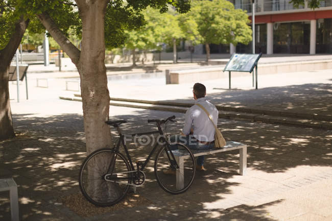 Вид сзади на человека, сидящего на скамейке в парке — стоковое фото