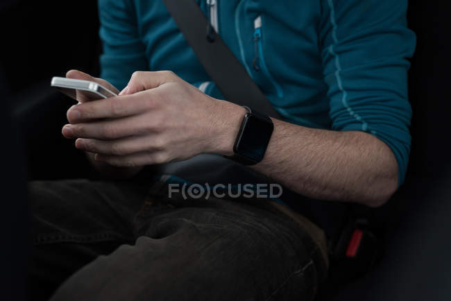 Mid section of man using mobile phone in car — Stock Photo
