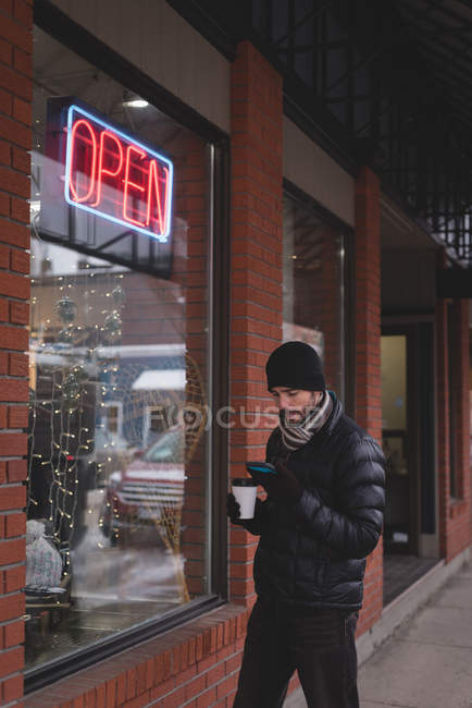 Jeune homme utilisant un téléphone portable à l'extérieur du magasin — Photo de stock