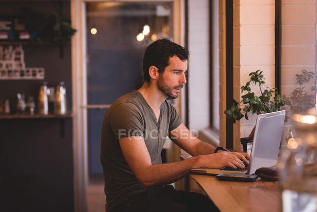 Молодий чоловік використовує ноутбук у кафе — стокове фото