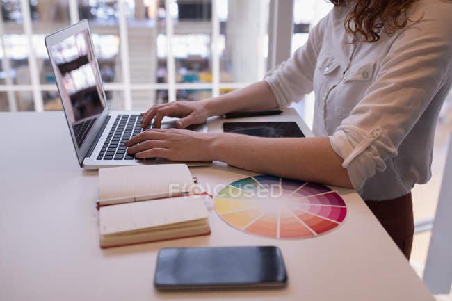 Mid section of female executive using laptop at desk in office — Stock Photo