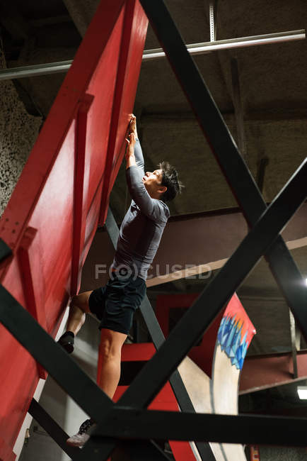 Man practicing rock-climbing on a wall in fitness studio — Stock Photo