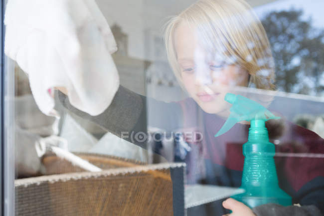 Мальчик моет окно тряпкой дома — стоковое фото