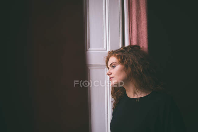 Mulher pensativa que se inclina na porta em casa — Fotografia de Stock