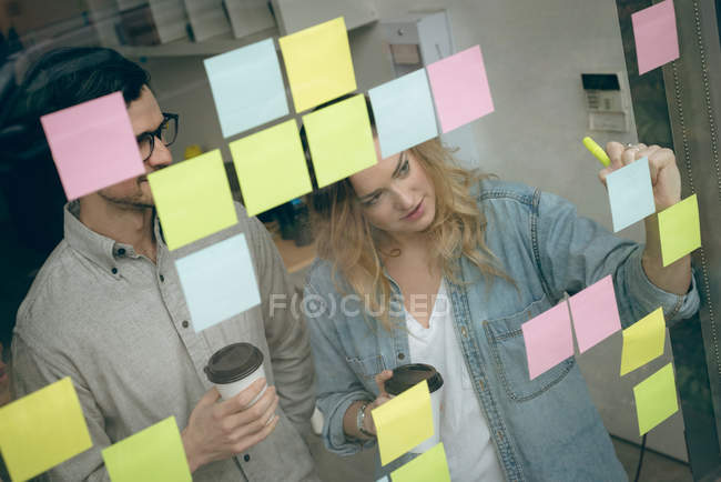 Business colleagues writing on sticky notes in office — Stock Photo