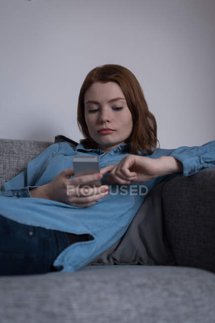 Молодая женщина с помощью смартфона в гостиной дома — стоковое фото
