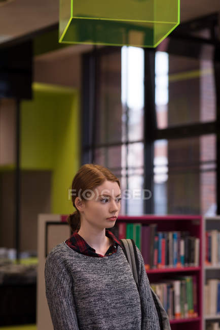 Thoughtful woman standing in the library — Stock Photo