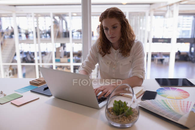 Ejecutivo femenino usando portátil en el escritorio en la oficina - foto de stock