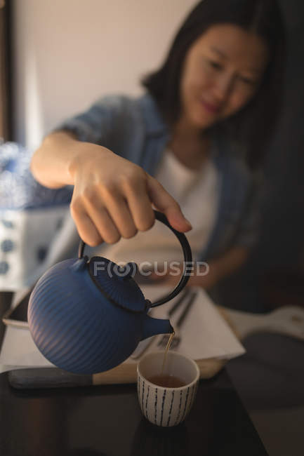 Femme enceinte versant du café noir dans une tasse au café — Photo de stock