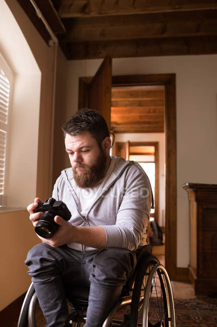 Homem com deficiência olhando para fotos na câmera em casa — Fotografia de Stock