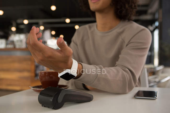 Hombre haciendo el pago a través de tarjeta de débito en cafetería - foto de stock