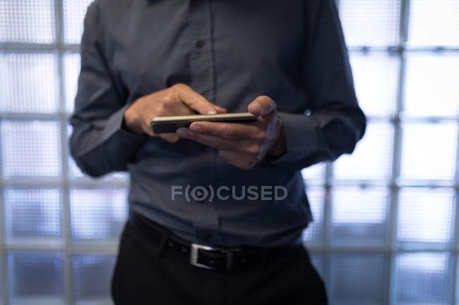 Seção média de homem de negócios usando um telefone inteligente no quarto de hotel — Fotografia de Stock