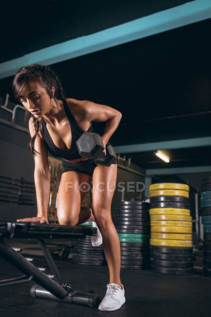 Mujer en forma haciendo ejercicio con pesas en el gimnasio - foto de stock