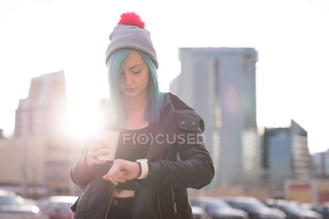 Elegante donna controllando il tempo su smartwatch mentre prende il caffè — Foto stock