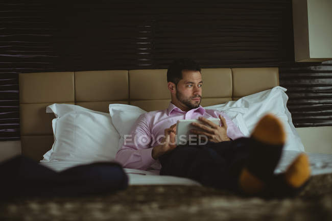 Empresário usando tablet digital no quarto de hotel — Fotografia de Stock