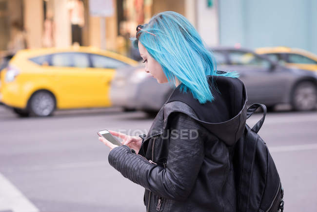 Stylish woman using mobile phone in city street — Stock Photo