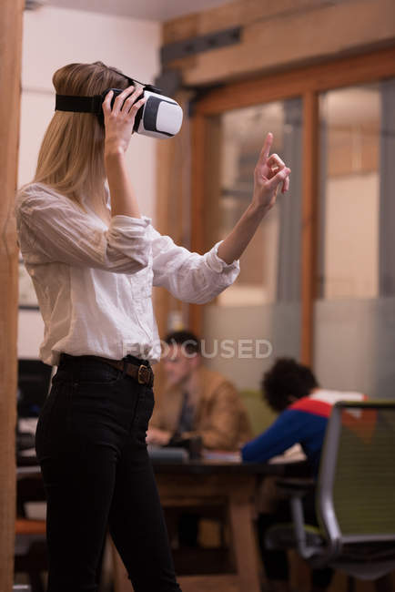 Female executive using virtual reality headset in office — Stock Photo