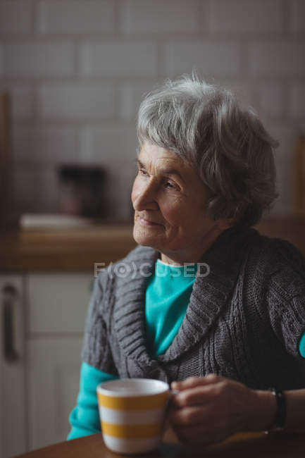 Femme âgée réfléchie prenant un café à la maison — Photo de stock