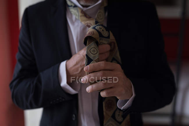 Primer plano del hombre de negocios atándose la corbata en la habitación del hotel - foto de stock