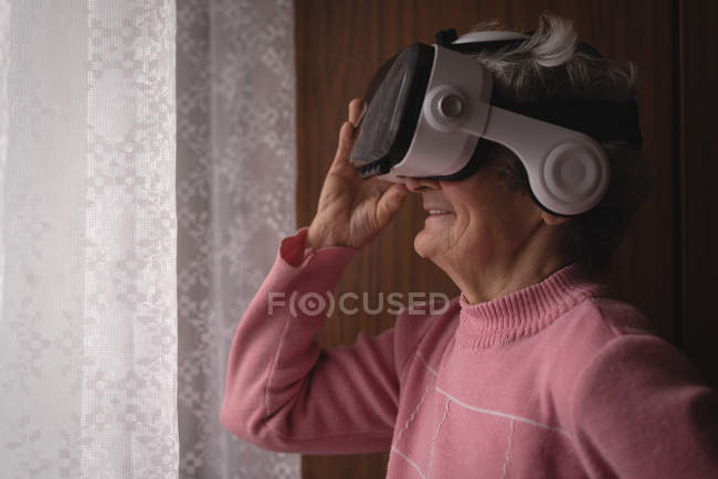 Donna anziana utilizzando auricolare realtà virtuale a casa — Foto stock