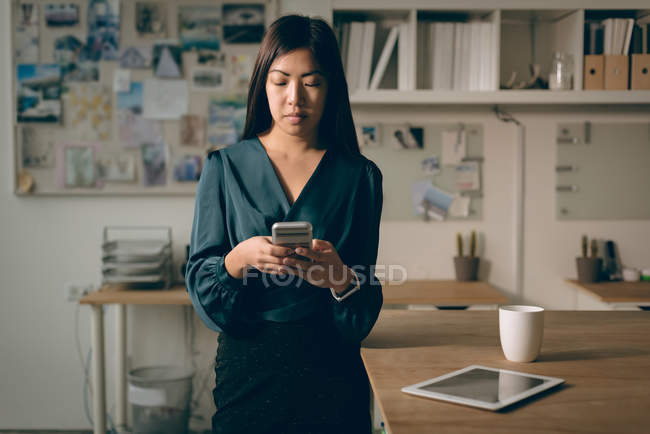 Жіночий керівник використовує мобільний телефон в офісі — стокове фото