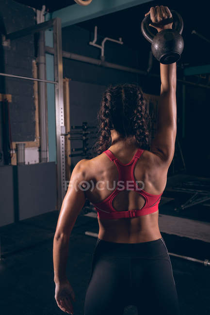 Vue arrière de la femme en forme faisant de l'exercice avec kettlebell dans la salle de gym — Photo de stock