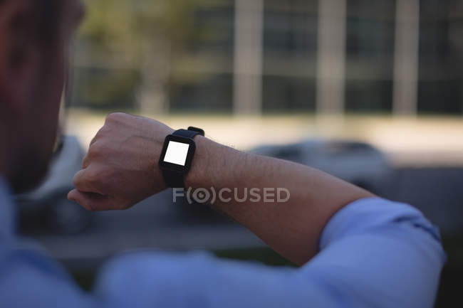 Man looking at smartwatch in city street — Stock Photo