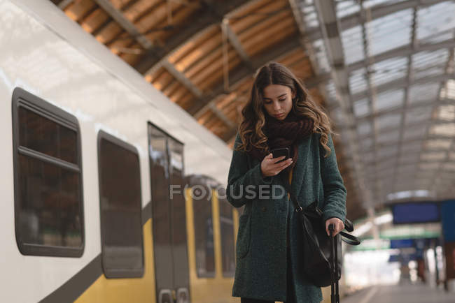 Mulher usando um telefone celular na estação ferroviária — Fotografia de Stock