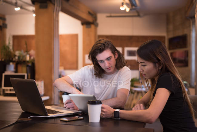 Бізнес-колеги обговорюють цифровий планшет за столом в офісі — стокове фото